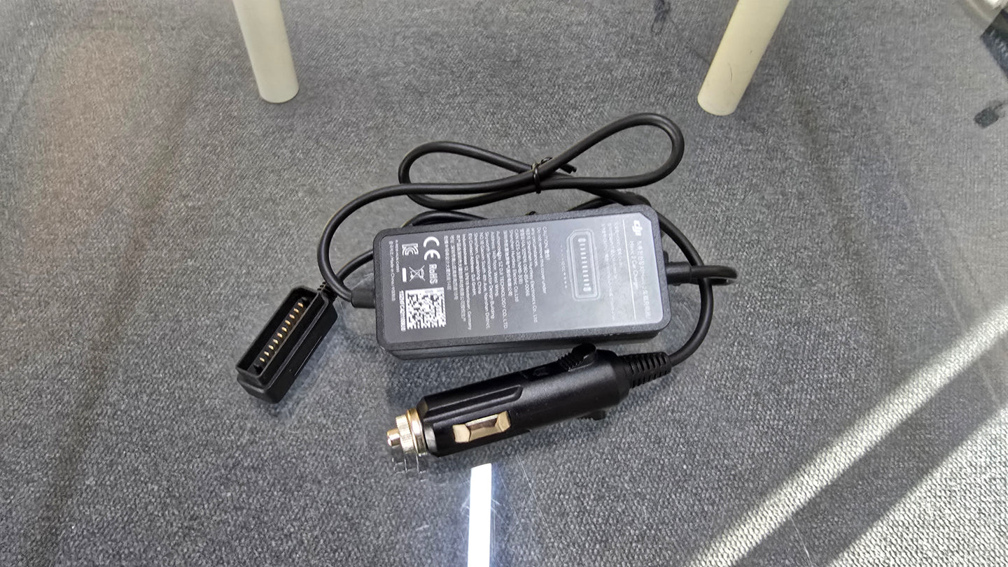 Pre-Owned DJI Mavic 2 car charger with cable on a surface, ideal for charging drones on the go.