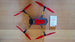 Top view of a drone with red propellers and a reflective tape safety instruction card.