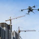 DJI Matrice 400 drone flying over construction site with cranes and buildings under development.