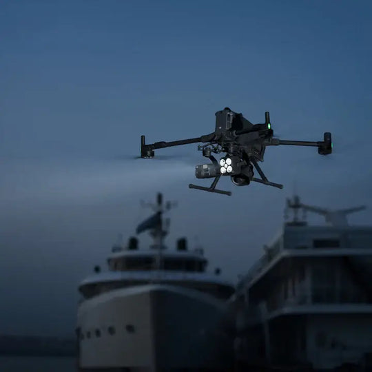 DJI Matrice 400 drone flying over boats at night with lights on for obstacle detection.