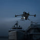 DJI Matrice 400 drone flying over boats at night with lights on for obstacle detection.