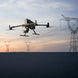DJI Matrice 400 drone flying against a sunset backdrop with power lines in the background.