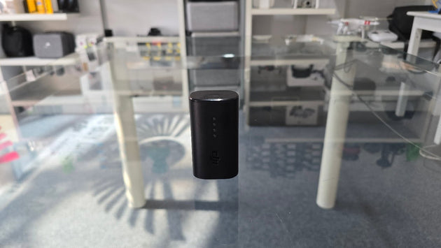 Pre-Owned DJI FPV Avata goggles battery displayed on a glass table in a modern store setting.