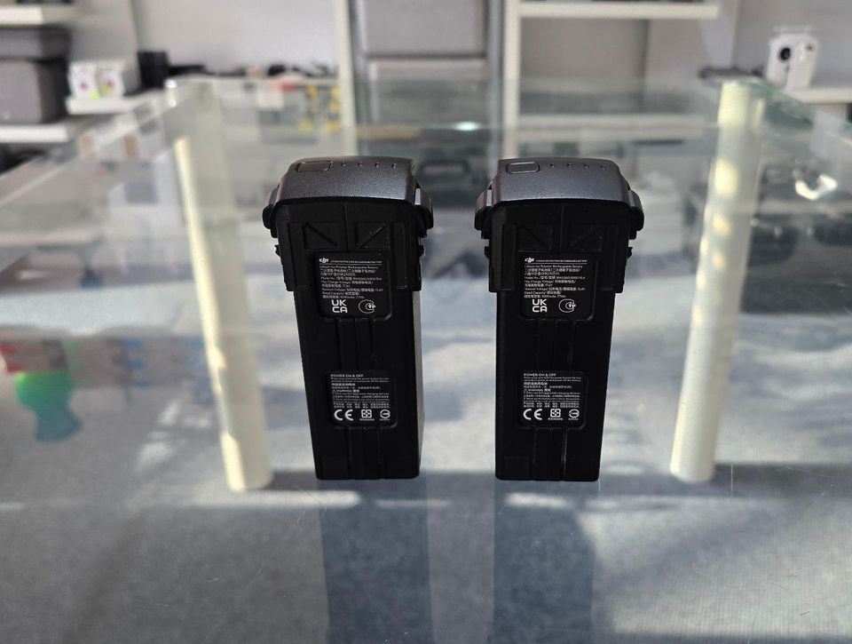 Pre-owned DJI Mavic 3 batteries displayed on a glass table, tested and healthy for drone use.