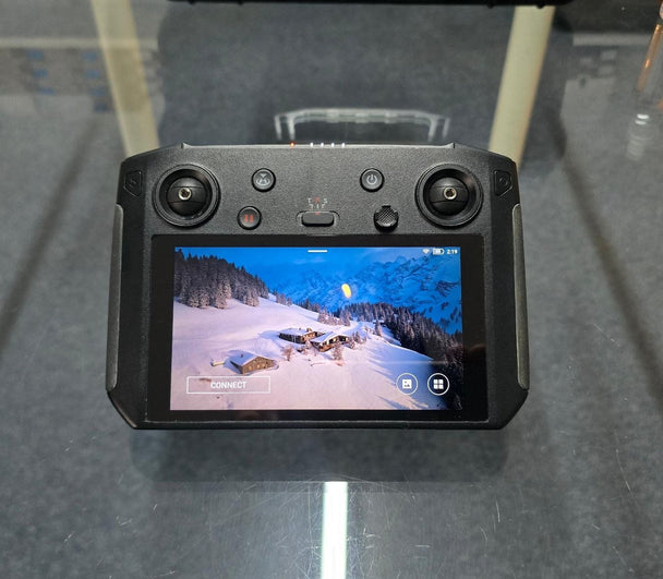 Pre-Owned DJI Smart Controller displayed on a surface, showing an aerial view of snowy landscape on the screen.
